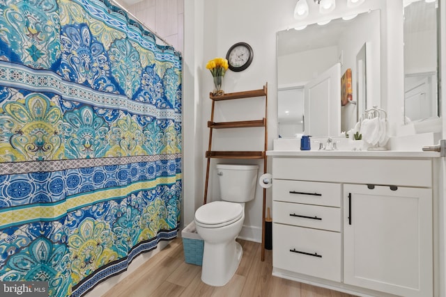 bathroom featuring toilet, a shower with curtain, wood finished floors, and vanity