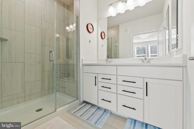 full bathroom featuring double vanity, a stall shower, a sink, and visible vents