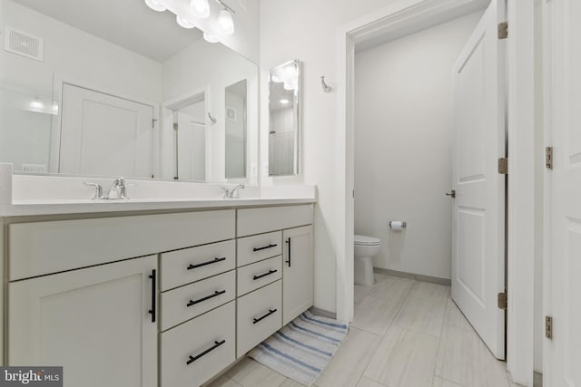 full bath with toilet, double vanity, visible vents, and a sink