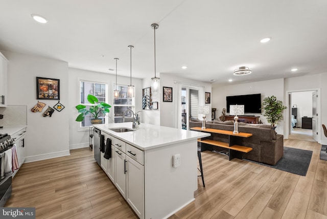 kitchen with light wood-style flooring, white cabinets, a sink, and recessed lighting