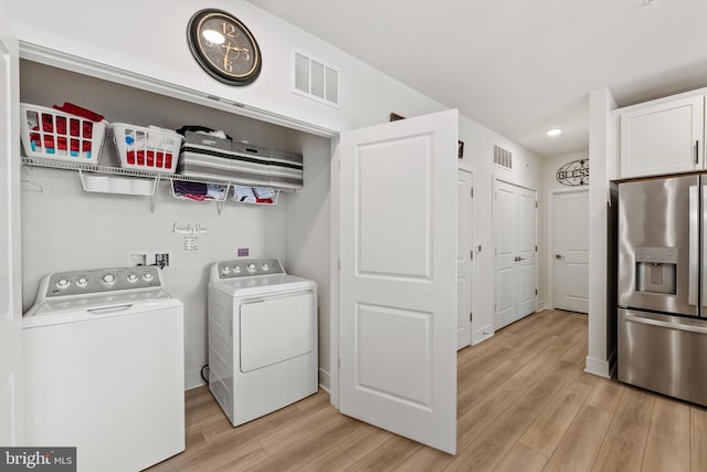 laundry room with laundry area, light wood-type flooring, independent washer and dryer, and visible vents