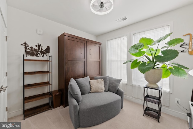 living area with light carpet, visible vents, and baseboards