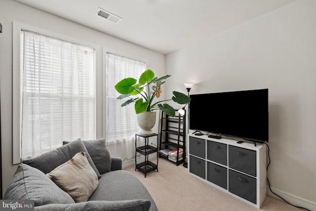 living area with visible vents and light carpet