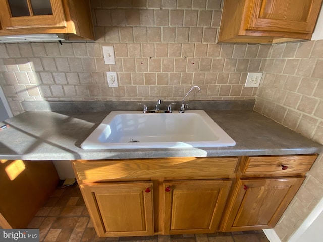 kitchen with backsplash, a sink, and brown cabinetry