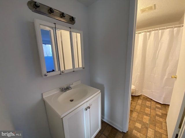 full bathroom with visible vents, a shower with shower curtain, toilet, a textured ceiling, and vanity