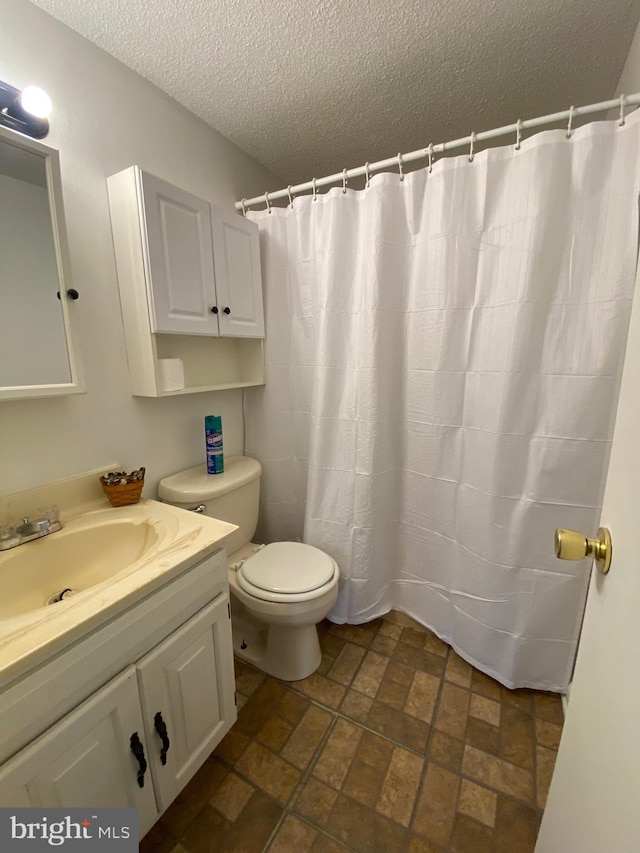 bathroom featuring a shower with curtain, vanity, toilet, and a textured ceiling