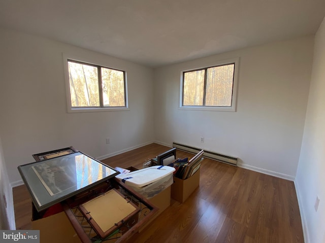 spare room featuring baseboards, a baseboard heating unit, and wood finished floors