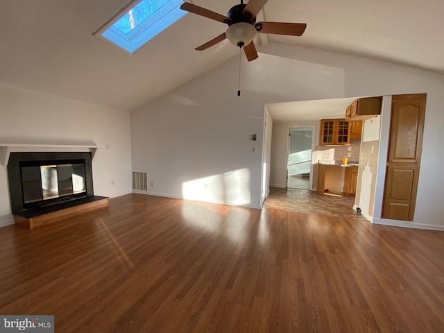 unfurnished living room with a skylight, visible vents, wood finished floors, and a multi sided fireplace