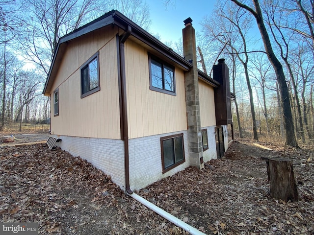 view of property exterior featuring a chimney and brick siding