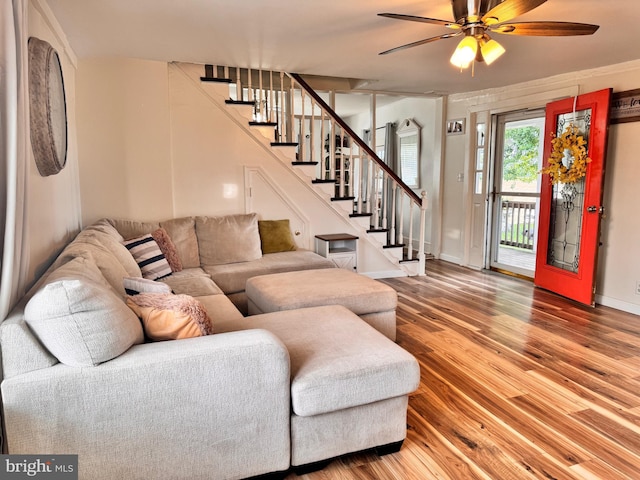 living room featuring baseboards, stairs, a ceiling fan, and wood finished floors