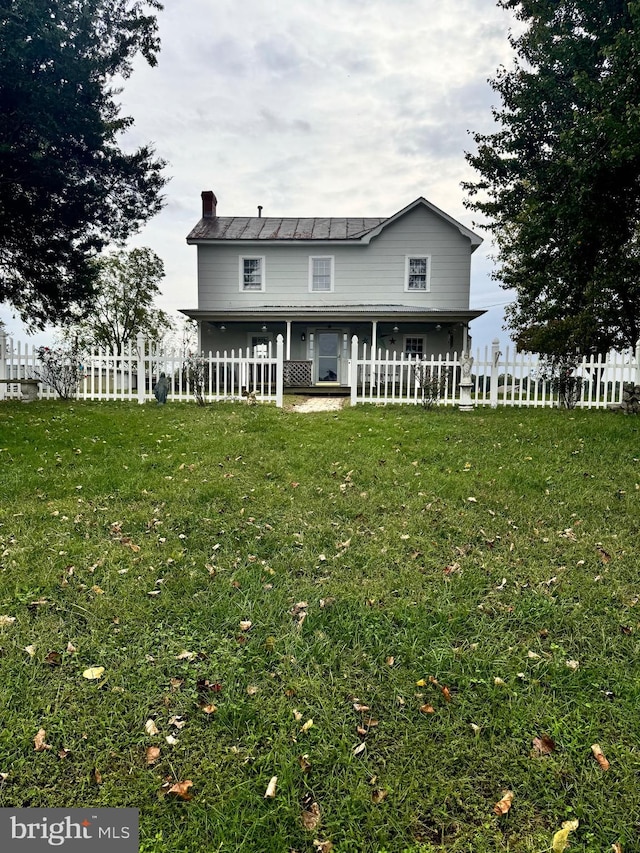 rear view of property featuring a chimney, fence, and a yard