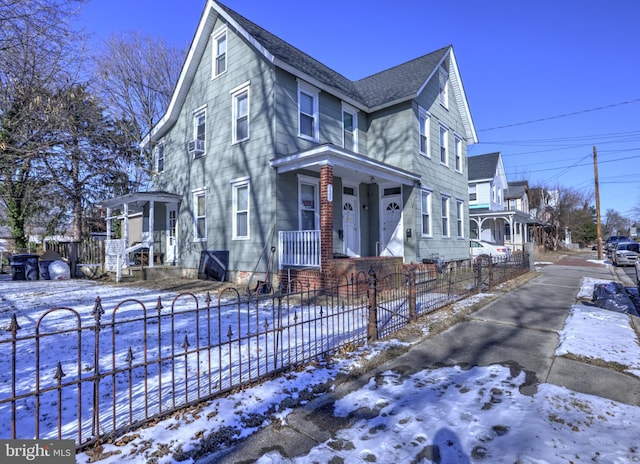 view of snowy exterior featuring a shingled roof and a fenced front yard