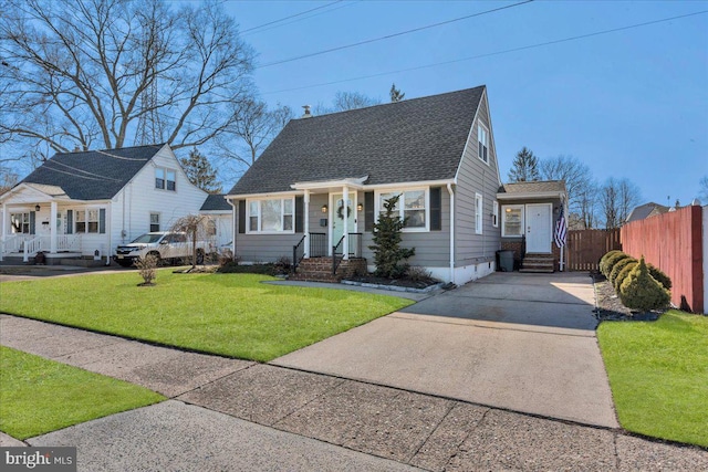 view of front of home with roof with shingles, fence, concrete driveway, and a front yard