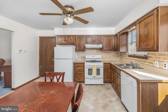 kitchen with under cabinet range hood, white appliances, a sink, light countertops, and backsplash