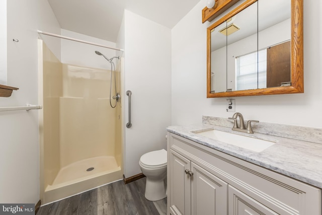 full bath with toilet, a walk in shower, wood finished floors, and vanity