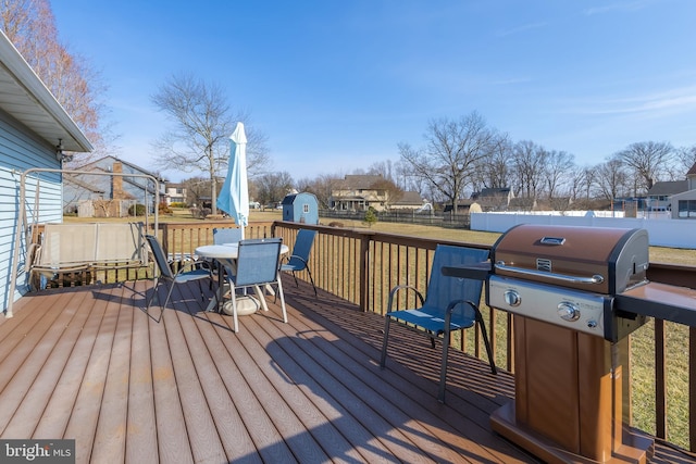 deck with outdoor dining area, a fenced backyard, an outdoor structure, and area for grilling