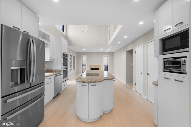 kitchen with appliances with stainless steel finishes, a center island, light wood-style flooring, and white cabinets