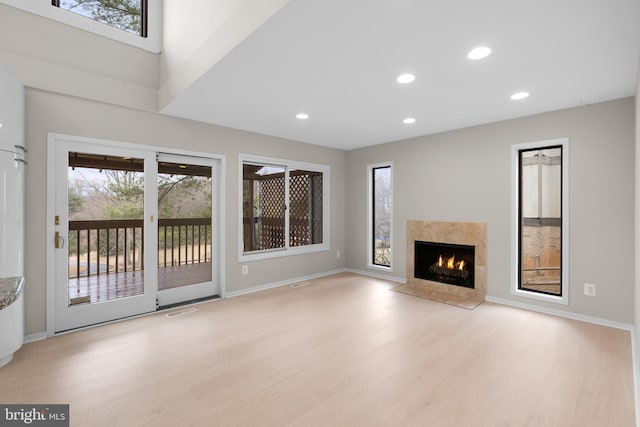 unfurnished living room with light wood finished floors, visible vents, baseboards, a premium fireplace, and recessed lighting