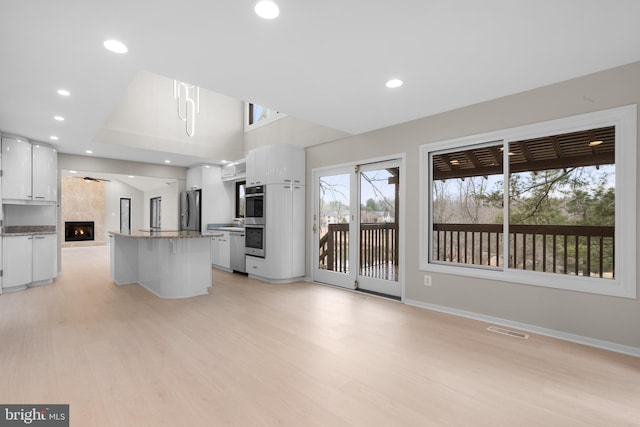 kitchen with stainless steel appliances, light wood-type flooring, white cabinets, and visible vents