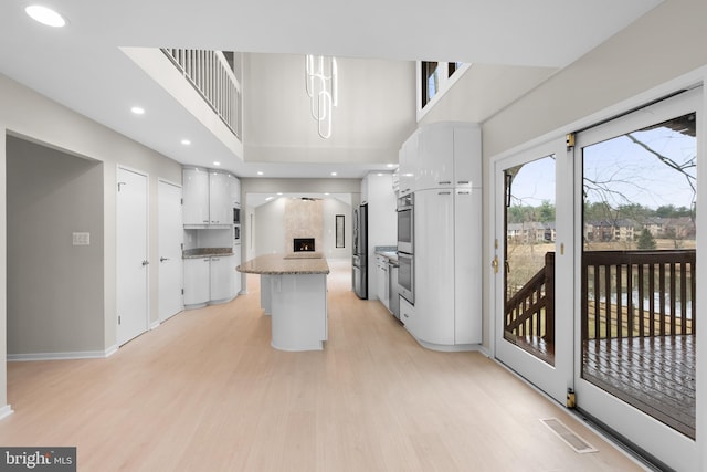 kitchen with visible vents, white cabinetry, light wood-style floors, appliances with stainless steel finishes, and a center island