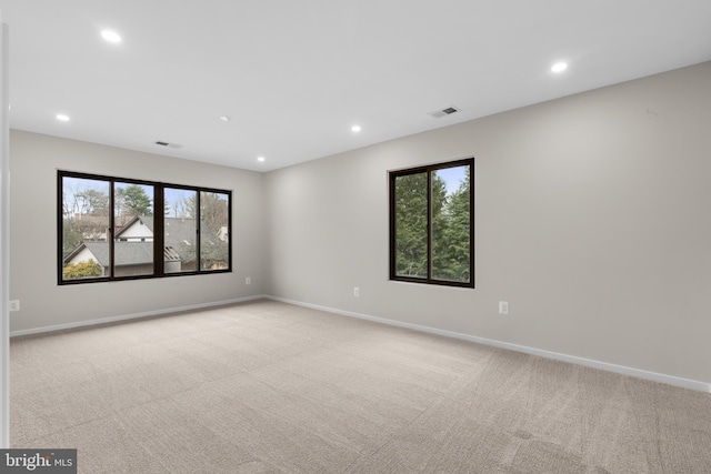 carpeted spare room featuring baseboards, visible vents, and recessed lighting