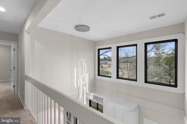 corridor with carpet, visible vents, and a wealth of natural light