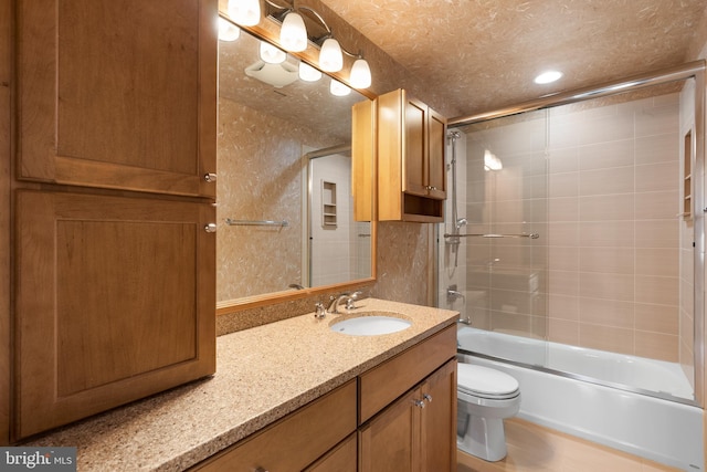 full bathroom featuring toilet, combined bath / shower with glass door, a textured ceiling, and vanity