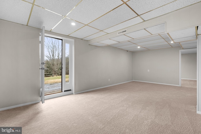 carpeted spare room featuring a paneled ceiling and baseboards