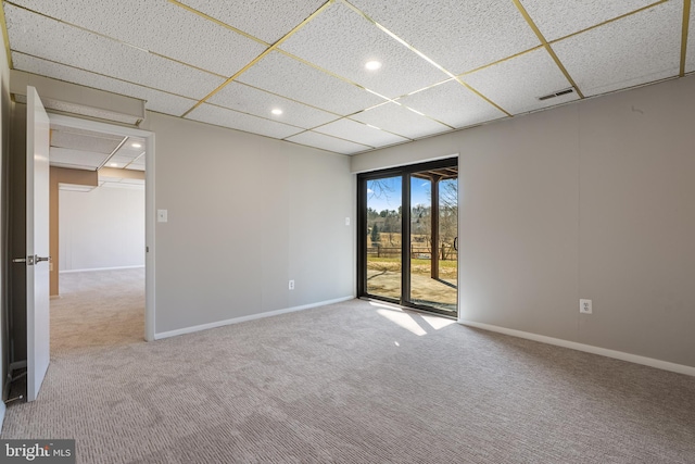 spare room with carpet floors, a drop ceiling, visible vents, and baseboards