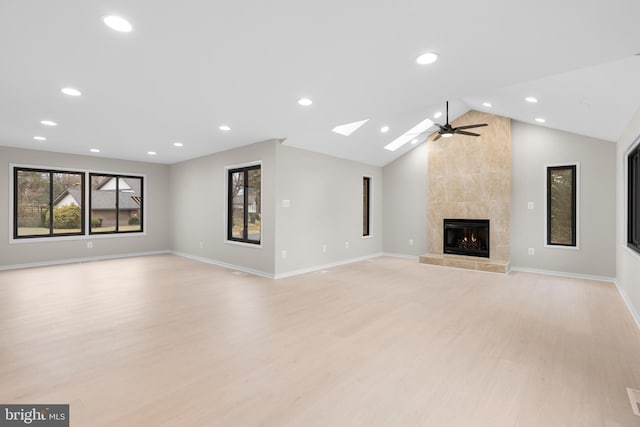 unfurnished living room featuring light wood finished floors, baseboards, a ceiling fan, vaulted ceiling, and a fireplace