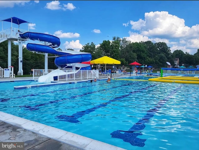 community pool featuring a water slide and fence