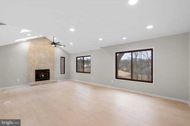 unfurnished living room featuring light wood-type flooring, visible vents, vaulted ceiling, and a tile fireplace