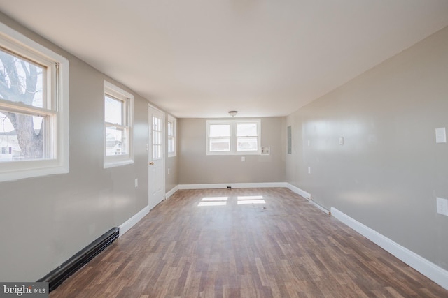 spare room featuring a baseboard radiator, baseboards, and wood finished floors