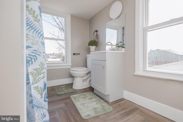 bathroom with toilet, parquet floors, baseboards, and vanity