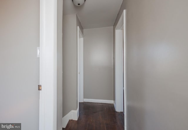 hallway featuring wood-type flooring and baseboards