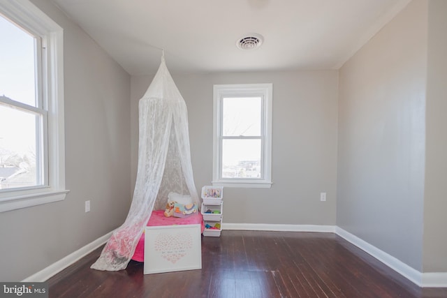 recreation room with hardwood / wood-style flooring, visible vents, and baseboards