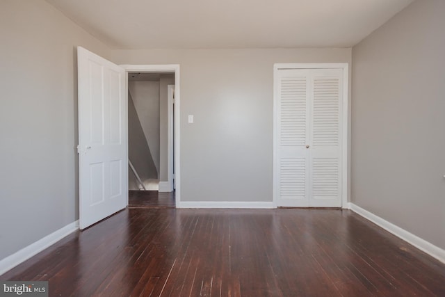 unfurnished bedroom with a closet, wood-type flooring, and baseboards