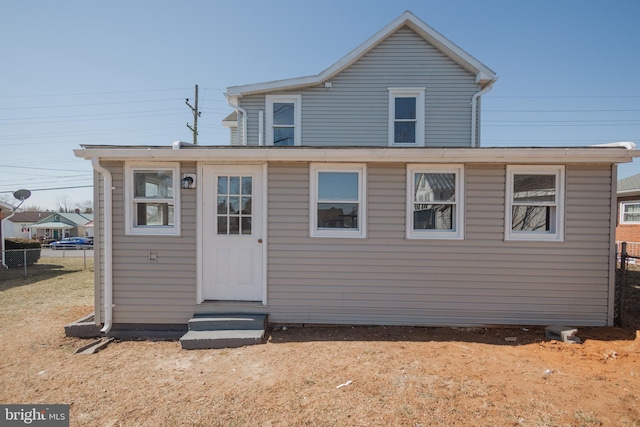 rear view of property with entry steps and fence