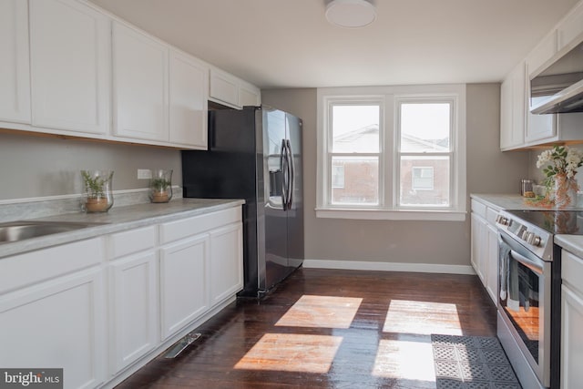 kitchen featuring appliances with stainless steel finishes, dark wood-style flooring, white cabinets, and baseboards