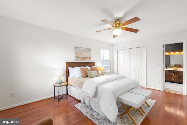 bedroom with a closet, ensuite bathroom, baseboards, and hardwood / wood-style flooring