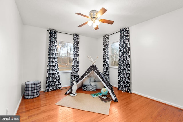 exercise room with ceiling fan, baseboards, and hardwood / wood-style floors