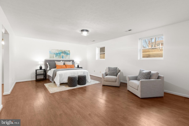 bedroom with wood finished floors, visible vents, and baseboards