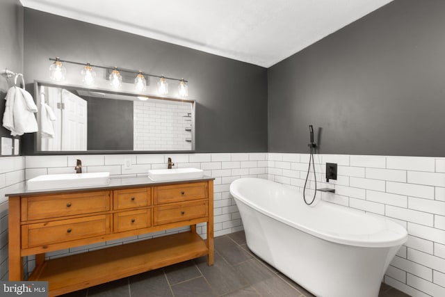 bathroom with double vanity, tile patterned flooring, a freestanding bath, and a sink