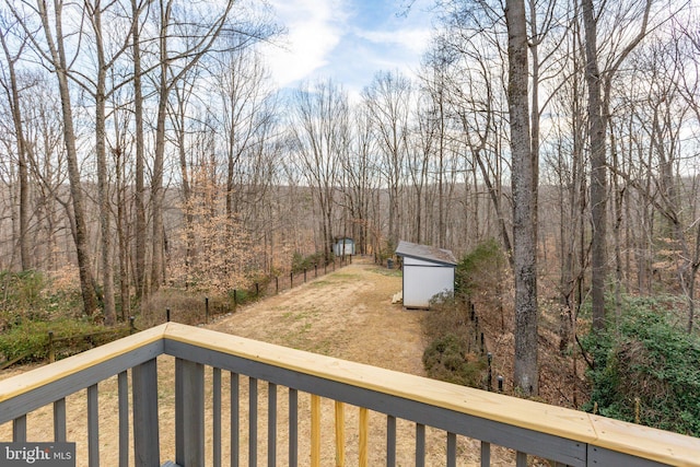 view of yard featuring a storage shed, an outdoor structure, fence, and a view of trees