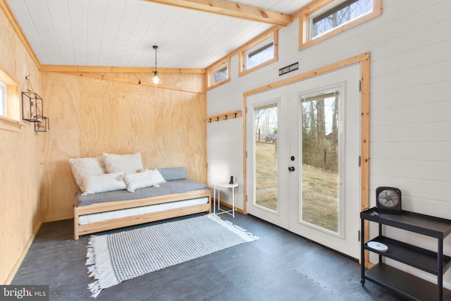 sitting room with french doors, vaulted ceiling with beams, wood walls, concrete flooring, and wooden ceiling