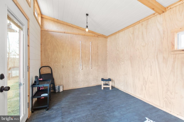 spare room with concrete floors, vaulted ceiling with beams, and wooden walls