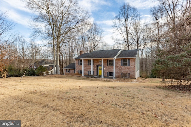 greek revival house with brick siding, a chimney, and a front yard