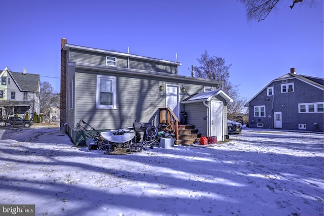 snow covered house featuring a chimney