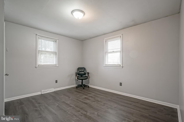 spare room featuring baseboards, visible vents, dark wood-type flooring, and a wealth of natural light