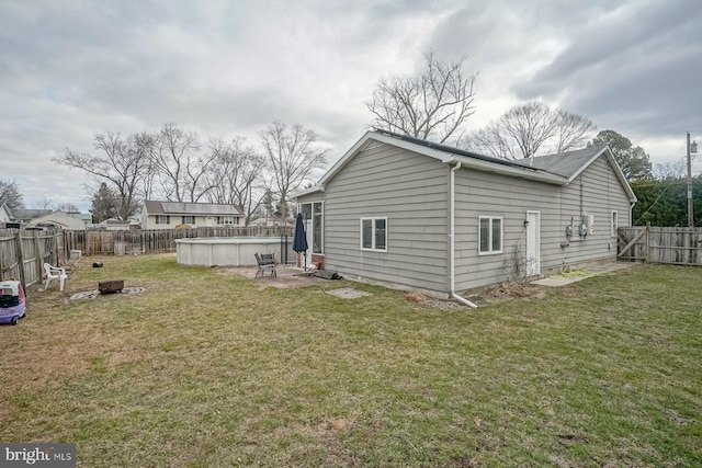 rear view of property with a fenced in pool, an outdoor fire pit, a fenced backyard, and a yard